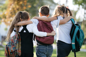 school friends a boy and two girls with school backpacks on thei